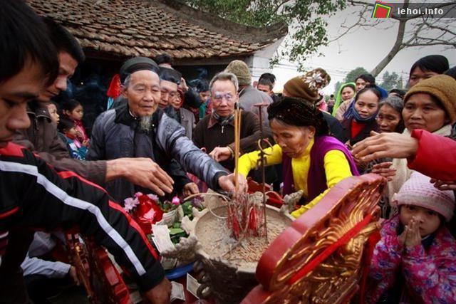 Người dân và khách xem hội đang thắp hương lên kiệu thánh