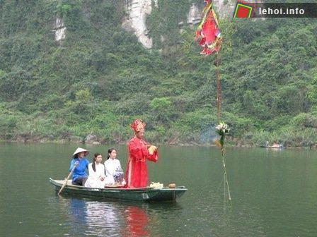 Chiếc thuyền chở ông chủ tế và 2 trinh nữ đang làm nghi thức bên cạnh cây tre trồng trên mặt sông