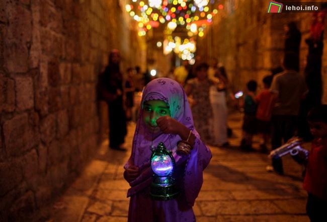 Một cô bé người Palestin đang đi trên đường phố của Jerusalem và cầm trên tay chiếc lồng đèn truyền thống của lễ Ramadan.
