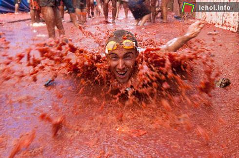 Một chàng trai đeo kính bơi và vùng vẫy thích thú giữa một biển cà chua. Ảnh: AFP